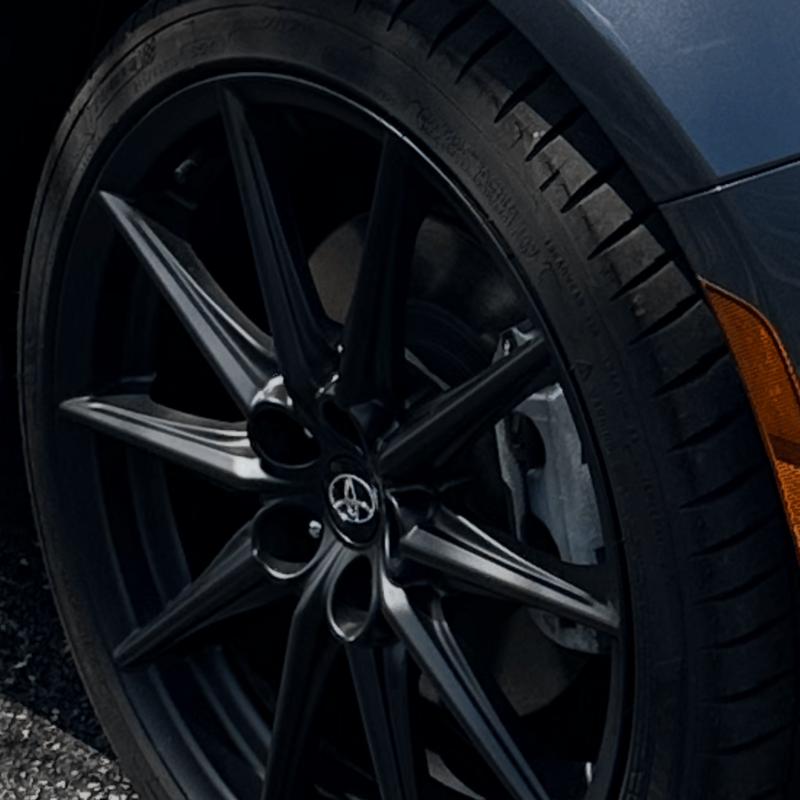 Detailed matte black alloy wheel and dressed tire on a Toyota sports car