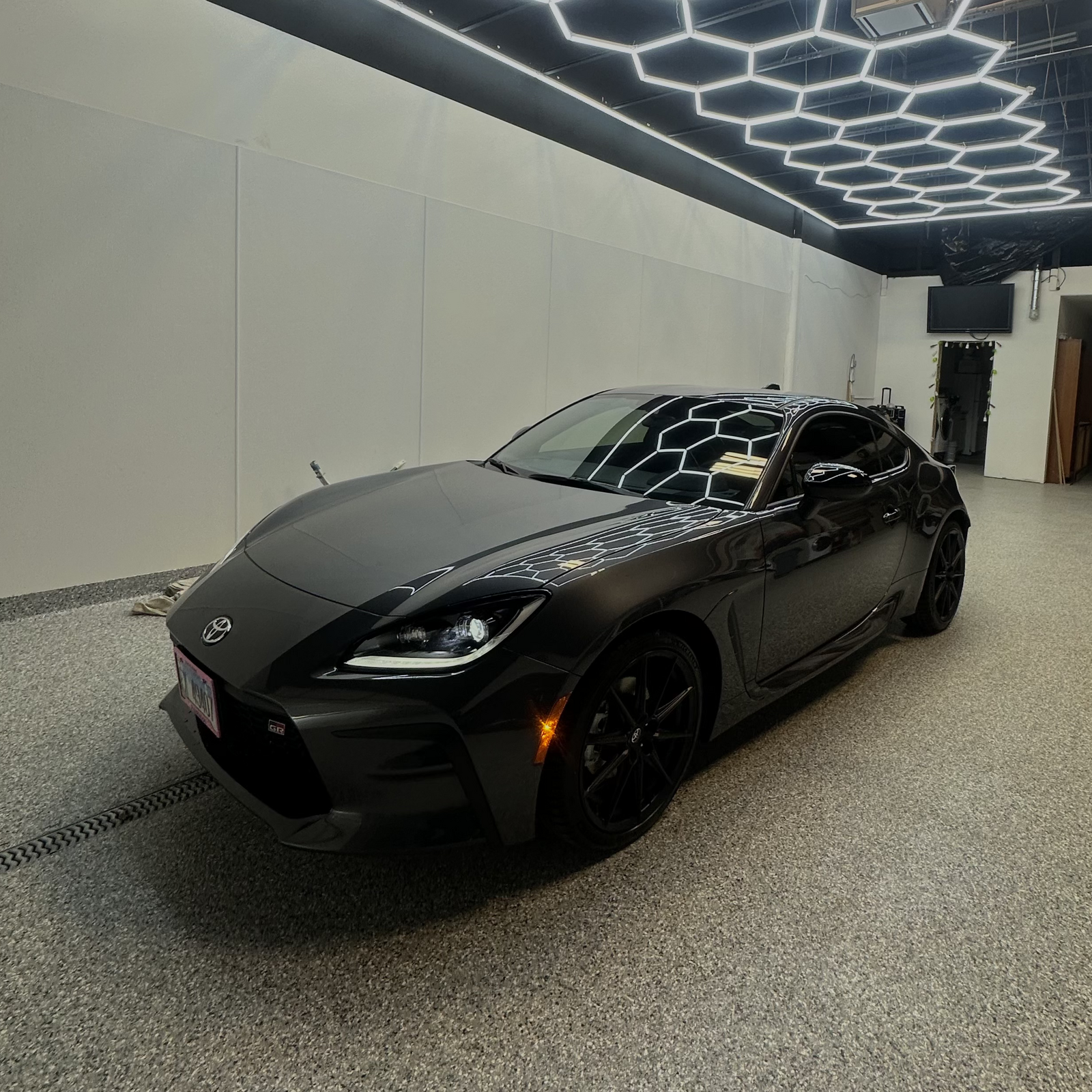 Dark grey Toyota GR86 sports coupe with a glossy ceramic-coated finish inside the detailing bay