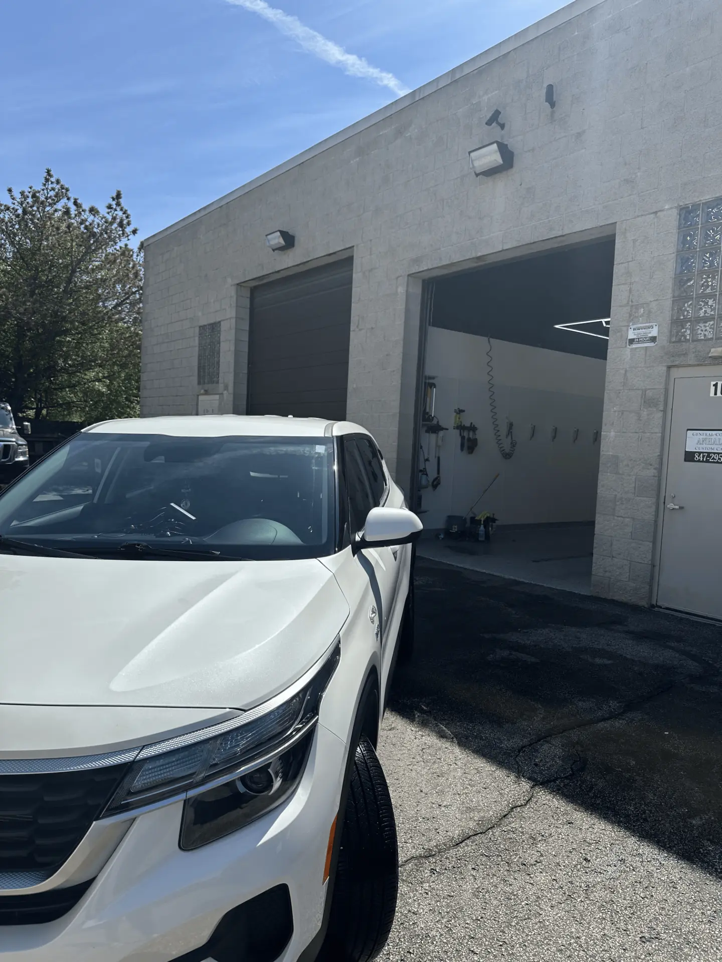 White Kia Seltos SUV detailed and parked outside the Virtue Auto Enhancement service bay