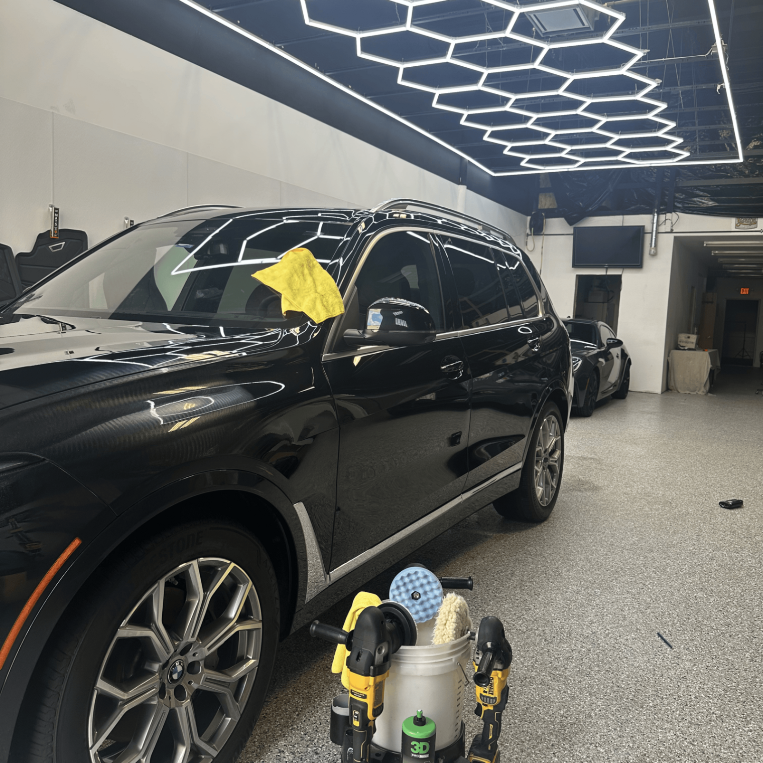 Black BMW X7 SUV freshly detailed under hexagon lighting in the Virtue Auto Enhancement studio